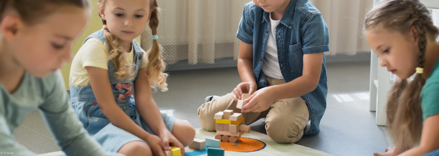 Gruppe spielender Kinder. Sitzen am Boden im Kreis.