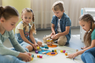 Gruppe spielender Kinder. Sitzen am Boden im Kreis.